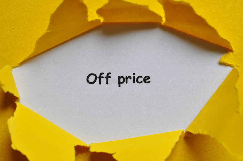 A close-up photograph of a torn yellow paper sheet revealing a white inner surface with the phrase 'Off price' written in black, rounded lowercase letters. The torn edges of the yellow paper curl outward, creating a jagged frame around the message. The background is primarily yellow, matching the outer paper. This image could be used on a webpage about affordable removal services by Maidavale Removals, highlighting cost-effective house relocation and packing options, and features a visual metaphor for uncovering savings or discounts related to removals and moving logistics.